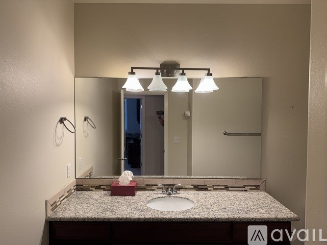 A bathroom with a granite countertop and a large mirror.