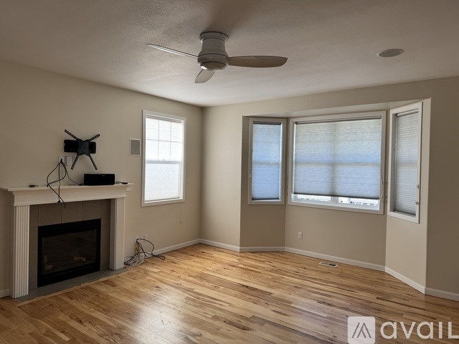 A living room with a fireplace and a ceiling fan.