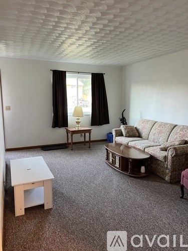 A living room with a sofa, a table, and a lamp.