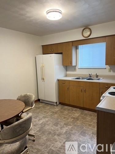 A kitchen with a table and chairs and a refrigerator.