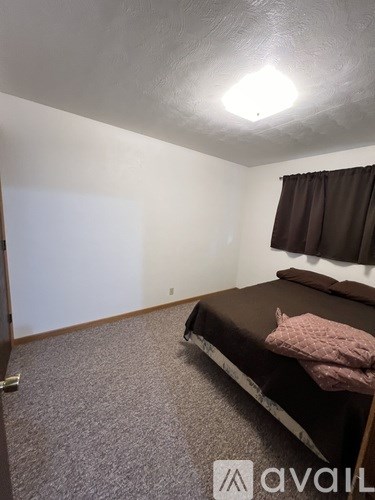 A bedroom with a bed and a window with curtains.