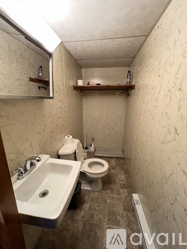 A bathroom with a toilet, sink, and mirror.