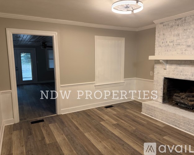 A room with a fireplace and a doorway leading to another room.