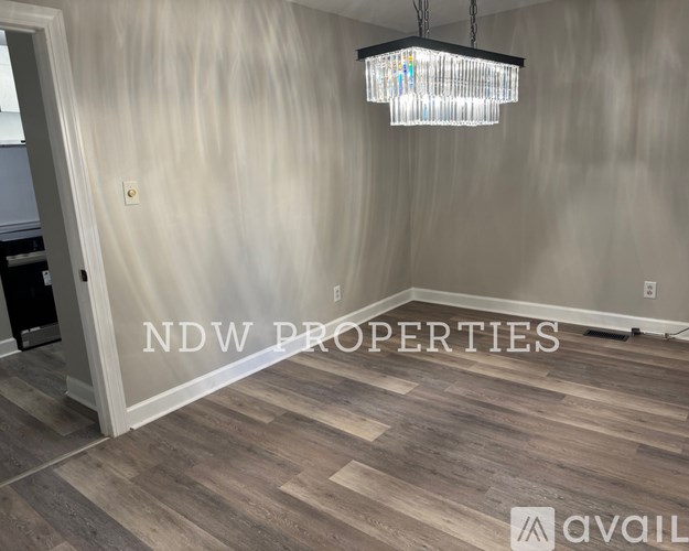 A room with wooden flooring and a chandelier hanging from the ceiling.
