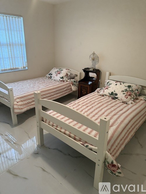 Two twin beds with striped bedspreads in a room with white walls.