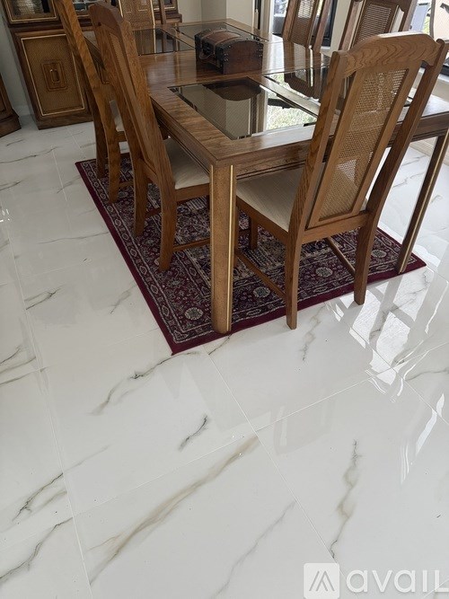 A dining table with chairs and a rug on a marble floor.