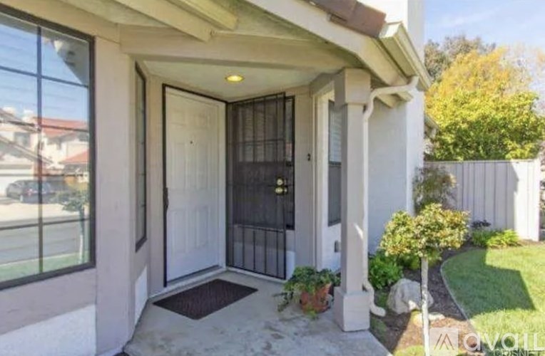 A white house with a black gate and a small garden.