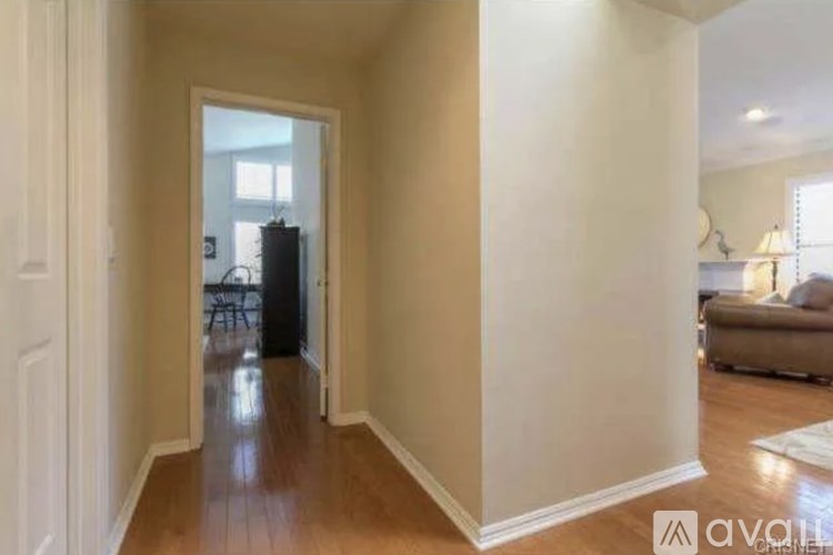 A hallway with a doorway leading to a living room.