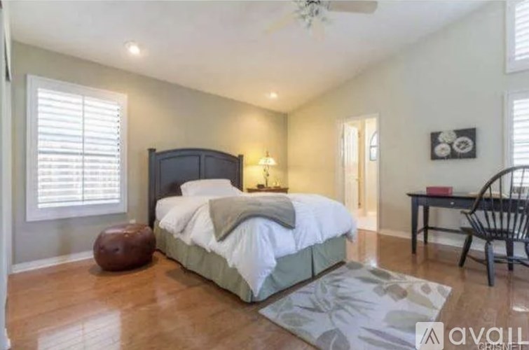 A bedroom with a large bed, a chair, and a ceiling fan.