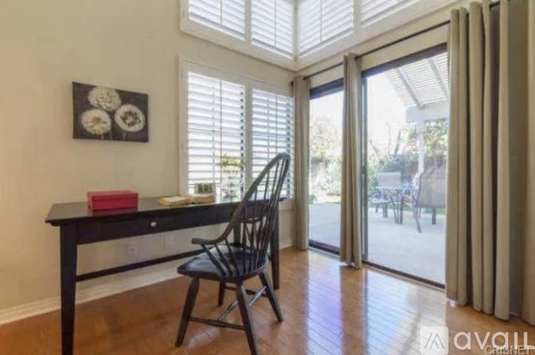 A black chair is placed in front of a desk with a red box on it.