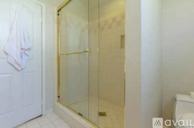 A white towel hangs on a white door in a bathroom.