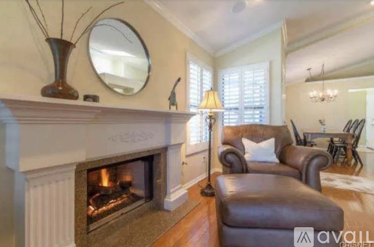 A living room with a fireplace, a brown leather chair, and a round mirror on the wall.