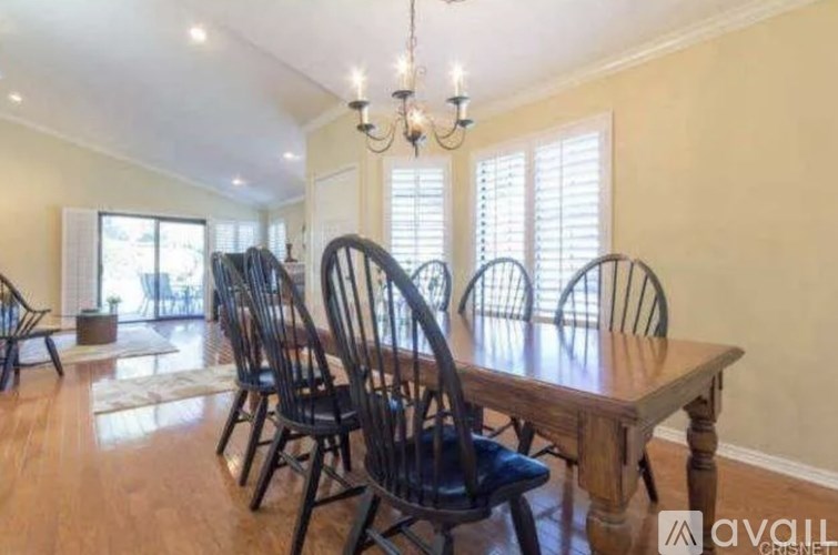 A dining room with a large wooden table and chairs.