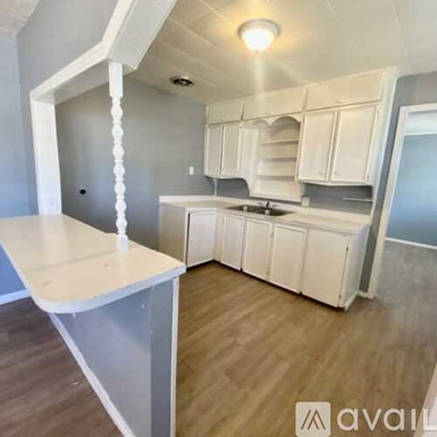 A kitchen with white cabinets and a wooden floor.