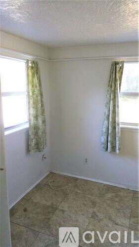 A room with a window and curtains is available for rent.