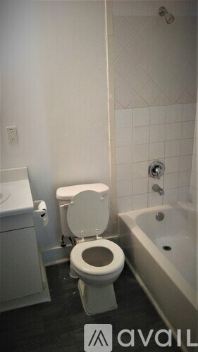 A white toilet in a bathroom with a white tub and sink.