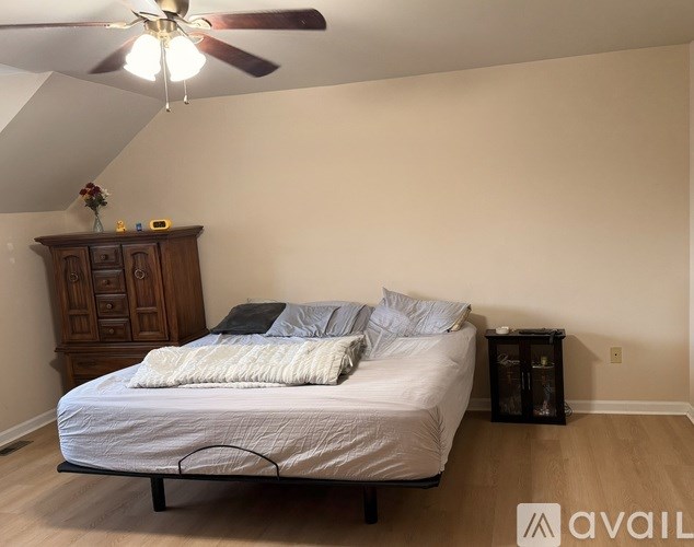 A bedroom with a bed, dresser, and ceiling fan.