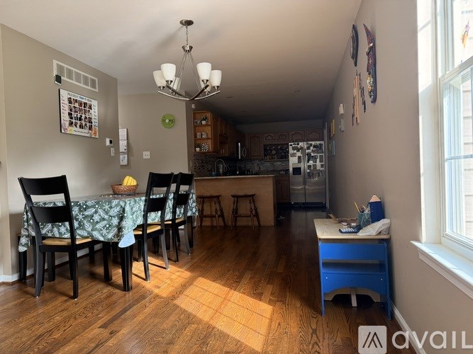 A dining room with a table set for four and a kitchen in the background.