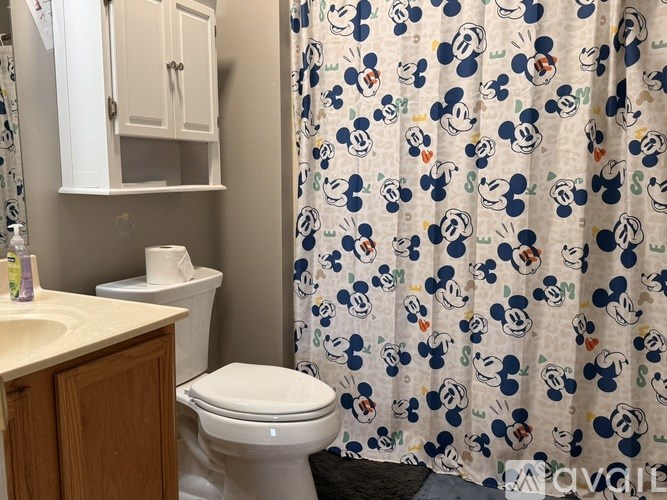 A bathroom with a toilet, sink, and shower curtain.