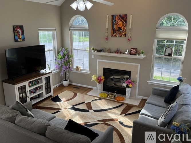 A living room with a grey couch, a fireplace, and a television.