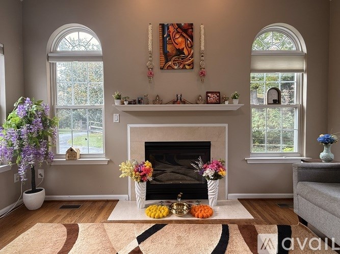 A living room with a fireplace, two vases with flowers, and a painting on the wall.