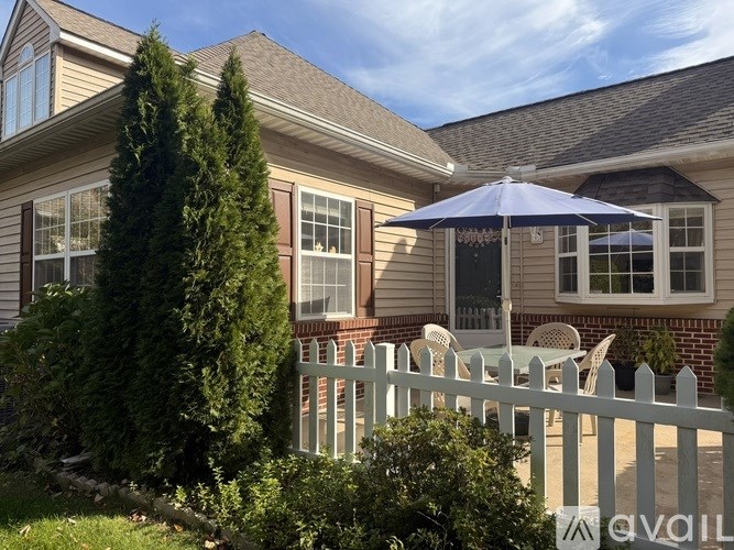 A house with a white picket fence and a blue umbrella.