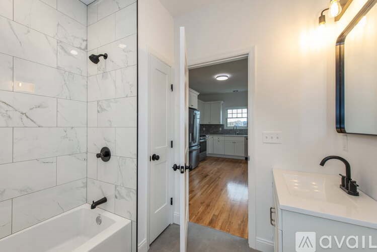 A bathroom with a marble tile shower and a white sink.