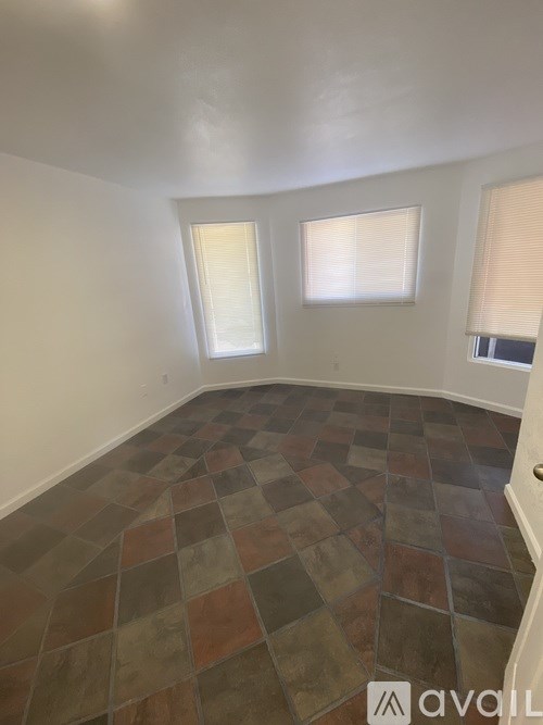 A room with a tiled floor and two windows.