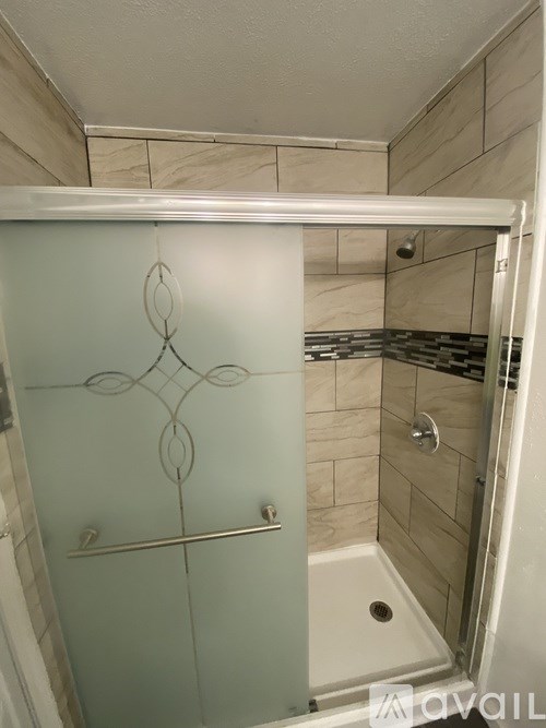 A shower with a glass door and a metal handle.