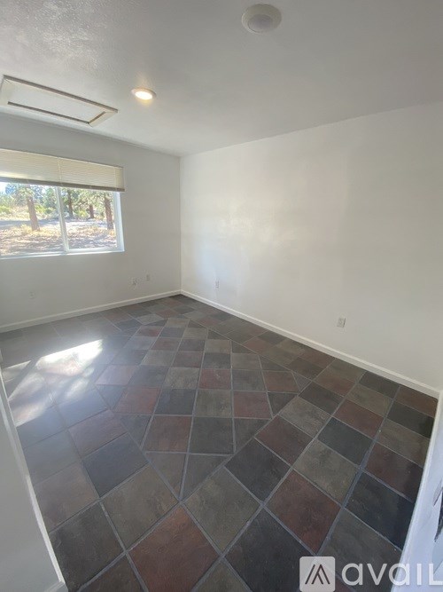 A room with a tiled floor and a window letting in sunlight.