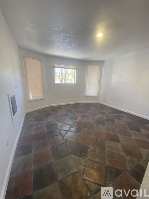 A room with a tiled floor and two windows.