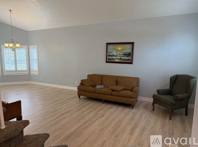 A living room with a brown couch, a chair, and a painting on the wall.