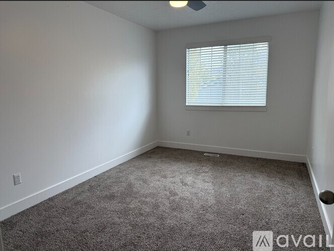 A room with a carpeted floor and a window with blinds.