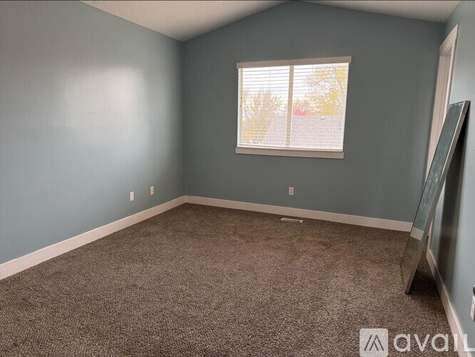 A room with a carpeted floor and a window with blinds.
