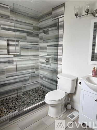 A white toilet sits next to a glass shower stall in a bathroom.