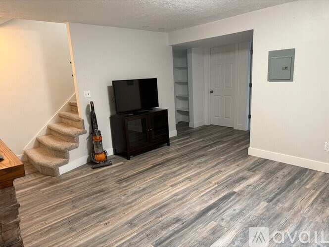 A living room with a staircase and a television.