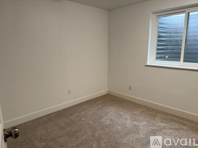 A room with a carpeted floor and a window with blinds.