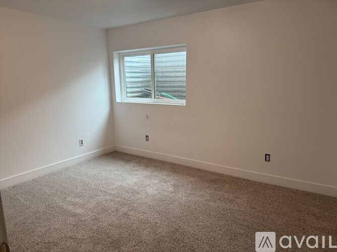 A room with a carpeted floor and a window with blinds.