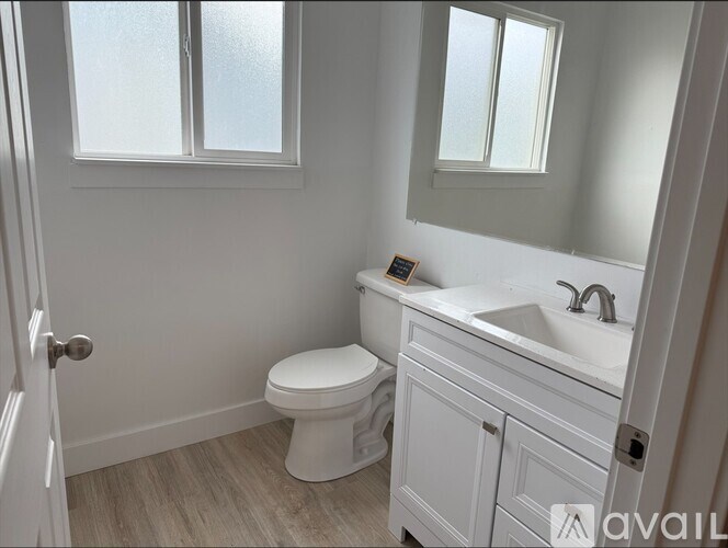 A white toilet sits in a bathroom next to a sink.