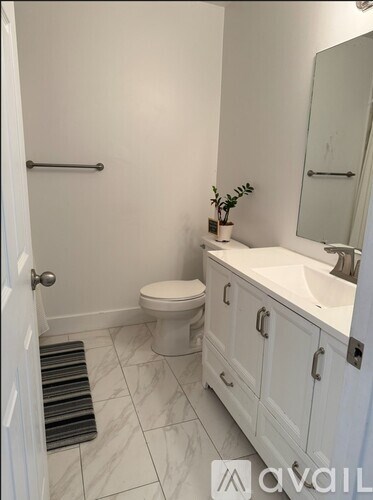 A bathroom with a toilet, sink, and mirror.