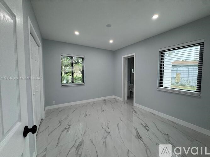 A spacious room with marble flooring and white walls.