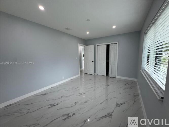 A spacious room with marble flooring and white walls.