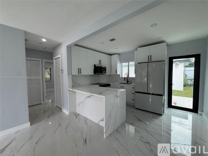 A modern kitchen with white cabinets and marble countertops.