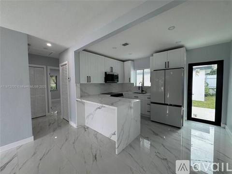 A modern kitchen with white cabinets and marble countertops.