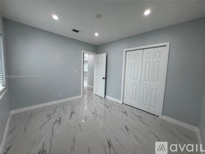 A spacious room with marble flooring and white walls.