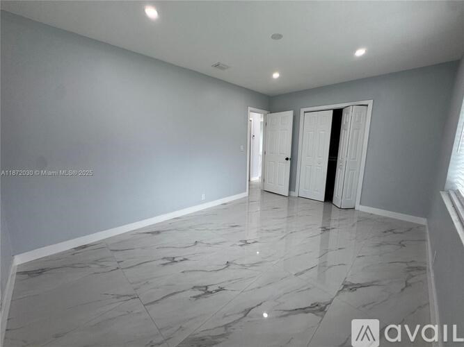 A spacious room with marble flooring and two doors.