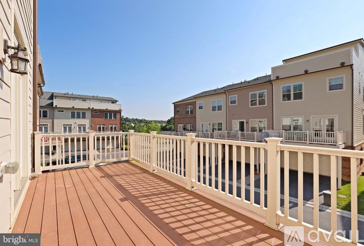 A wooden deck with a railing and a building in the background.