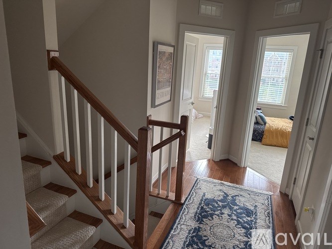 A hallway with a staircase and a rug on the floor.