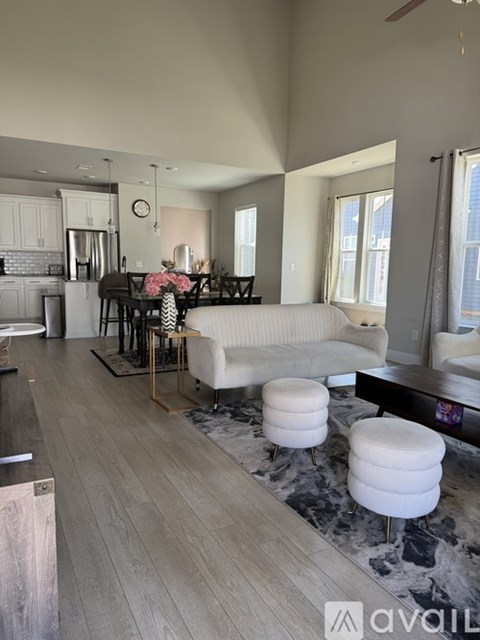A living room with a white couch and a dining table with chairs.