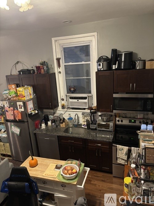 A kitchen with a refrigerator, oven, and a table with food on it.